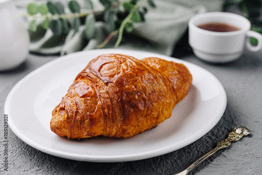 Croissant on plate with cup of Tea