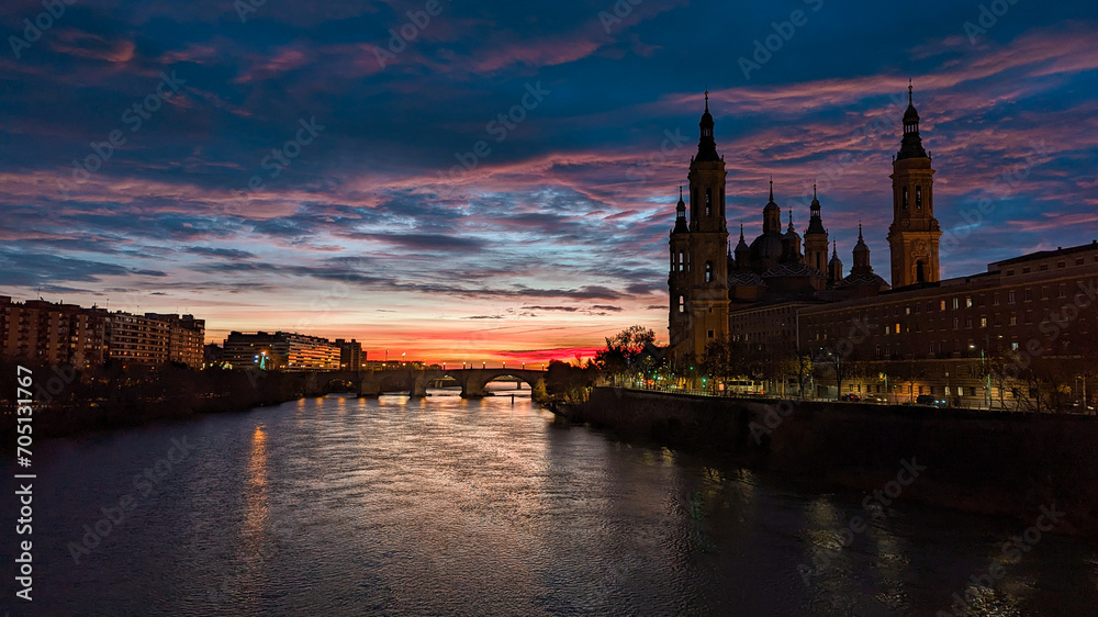 Echoes of Light: Winter Sunrise at Basilica del Pilar in Zaragoza, Painting the Sky and Ebro River with Warm Hues.
