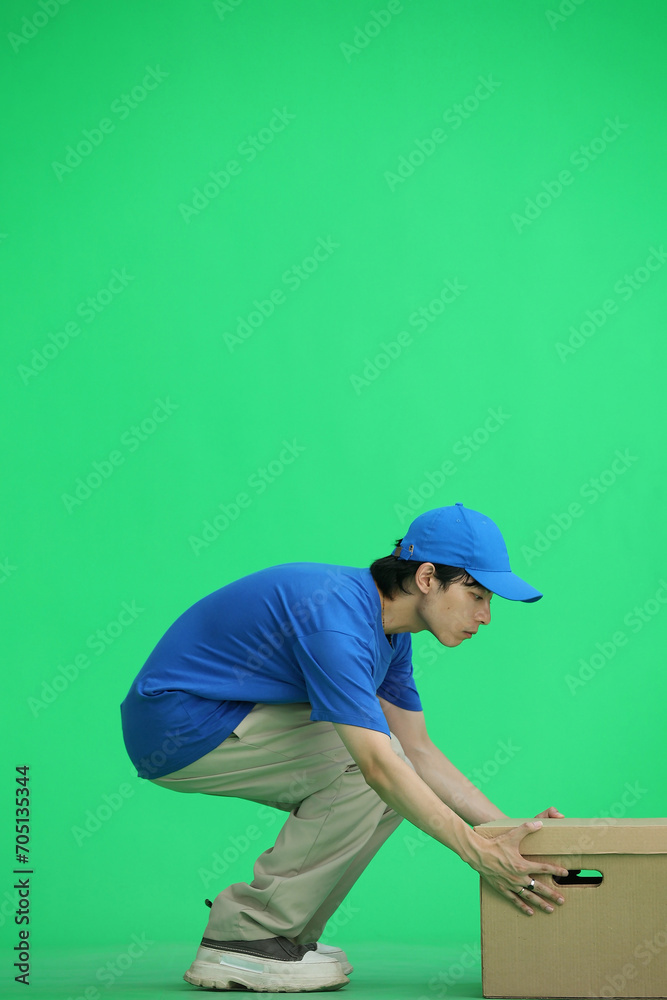 The delivery guy, on a green background, in full height, puts a box