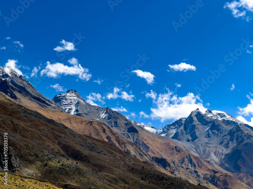 Cold climate landscape of the snow capped mountains with clouds and blue sky