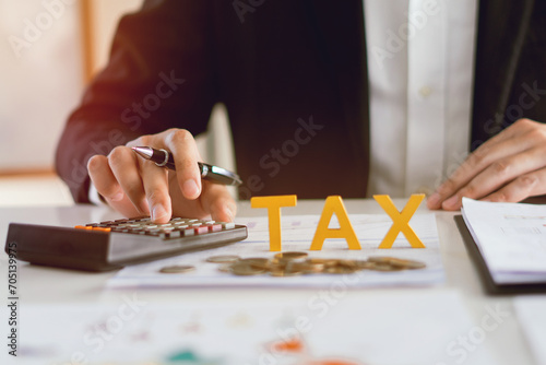 Tax Gold wooden text , Pay tax in 2024 years, Man Using calculator to calculate Individual Income and the new year 2024 Filling out writing taxes online tax concept. photo