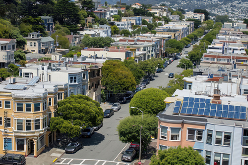 Aerial view of a sunny urban neighborhood with distinctive architecture, solar panels, and lush greenery amidst residential streets.