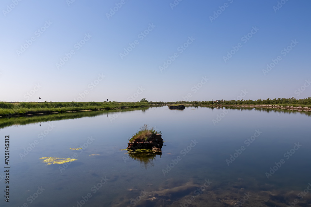 Scenic view of Parco del Delta del Po in Veneto, Italy. Untouched wetlands and nature in Po Delta. Raw wilderness on Via delle Valli Rovigo Province. Large lake in serene unspoiled natural habitat Scenic view of Parco del Delta del Po in Veneto, Italy. Untouched wetlands and nature in Po Delta. Raw wilderness on Via delle Valli Rovigo Province. Large lake in serene unspoiled natural habitat