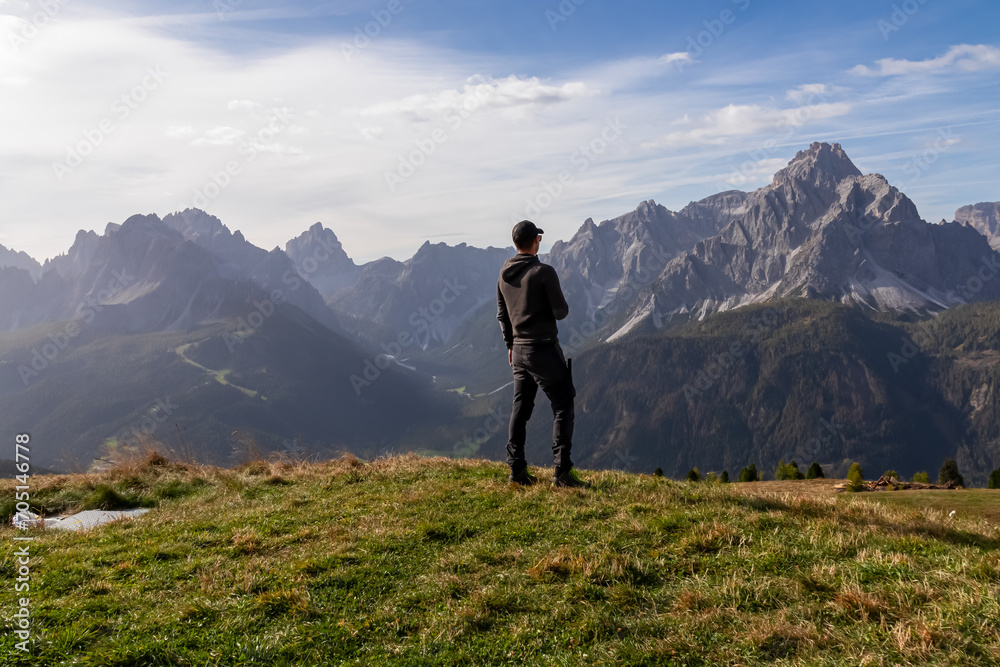 Hiker man with scenic view of majestic mountain peaks of untamed Sexten Dolomites in South Tyrol, Italy, Europe. Hiking on Monte Elmo in autumn. Wanderlust concept in Italian Alps. Tranquil atmosphere