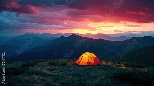 Glowing orange tent in the mountains under dramatic evening sky. Red sunset and mountains in the background. Summer landscape