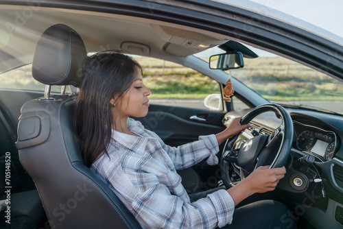 Portrait of a young woman sitting in a car and  holding on to the steering wheel. Buy your first car concept