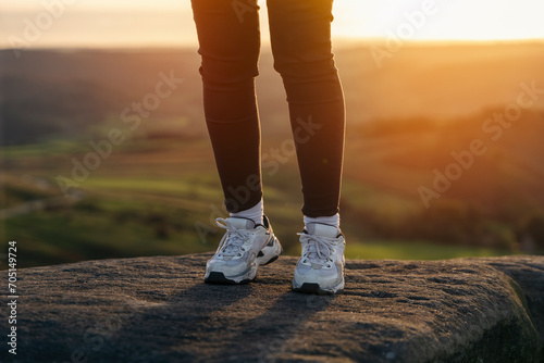 A woman walking on a rocks  on the mountain trail at cold autumn evening. Hiking and active lifestyle concept toned image