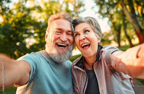 Portrait of a positive, confident, smiling gray-haired couple of senior people holding a phone camera, taking a photo, grimacing. Senior people are emotionally happy and enjoying life.
