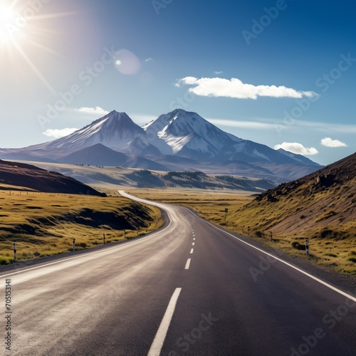 Road through a mountain valley with snow capped mountains in the distance
