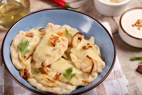 Dumplings, pierogi or vareniki with potato or meat filling. Served with dill, roasted onion and sour cream sauce. Polish or Ukrainian cuisine. Delicious homemade dish.