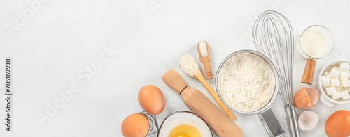 Ingredients for baking eggs, flour, sugar, butter, milk and rolling pin on light table. Long banner format. top view. copy space for text