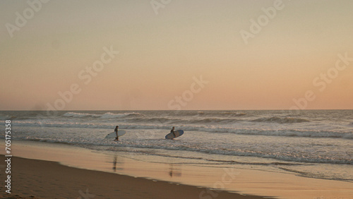 sunset on the beach with surfers