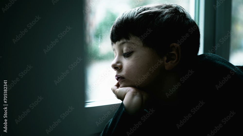 Bored Child Expressing Annoyance, Deep Sigh at Home with hand in chin by window. Child struggling with boredom Bored Child Expressing Annoyance, Deep Sigh at Home with hand in chin by window. Child struggling with boredom