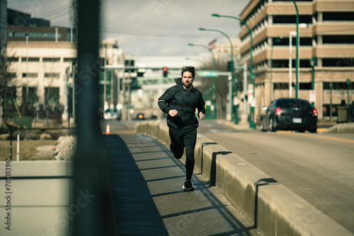 Young man jogging on city bridge