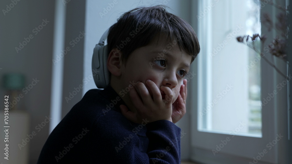 Thoughtful small boy with hand in chin daydreaming at home by window. Pensive child thinking deeply absorbed in introspective thoughts Thoughtful small boy with hand in chin daydreaming at home by window. Pensive child thinking deeply absorbed in introspective thoughts