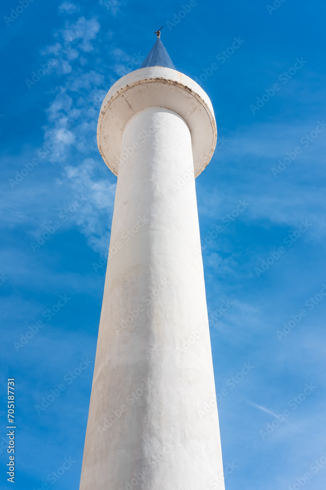 White mosque minaret. Mosque minaret with blue sky in the background White mosque minaret. Mosque minaret with blue sky in the background