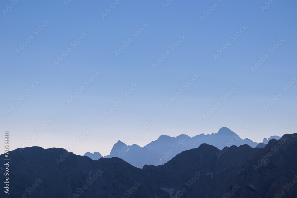 Obraz premium Silhouette of mountain peaks of wild Julian Alps seen on scenic hiking trail to majestic summit Mangart, Friuli Venezia Giulia, border Italy Slovenia, Europe. Hiking wanderlust in alpine wilderness