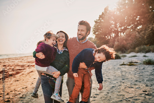 Happy young mother and father with two little children at the beach photo