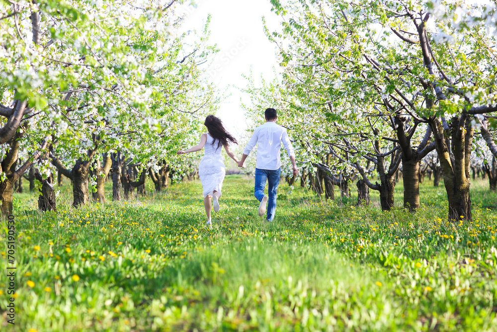 Young couple in love running in spring blossom garden Young couple in love running in spring blossom garden