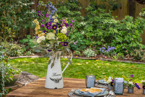 Garden scene for outdoor entertaining and decoration. Watering Can and pitcher, flowers, garden themed Spring and Summer scene for the residential home backyard