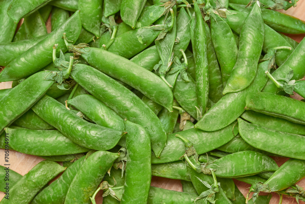 green ripe plucked pea pods on a wooden kitchen cutting board close-up. flat lay green ripe plucked pea pods on a wooden kitchen cutting board close-up. flat lay