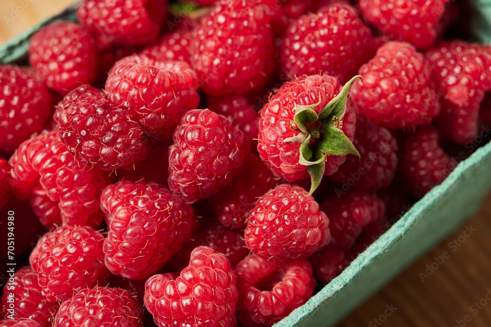 delicious fresh raw red raspberries in natural eco-friendly packaging in a green cardboard basket on a wooden table close-up. harvest. healthy food. diet. summer. vitamins delicious fresh raw red raspberries in natural eco-friendly packaging in a green cardboard basket on a wooden table close-up. harvest. healthy food. diet. summer. vitamins
