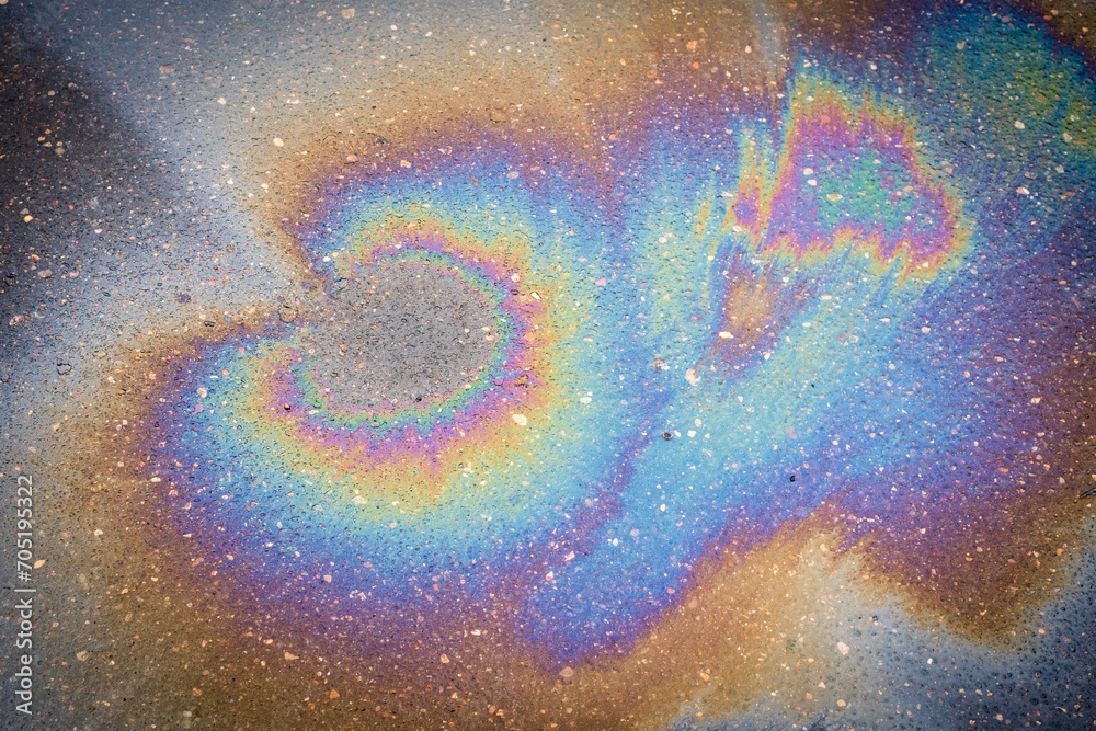 Fototapeta premium Texture plan of an iridescent oil or gasoline spill on wet pavement, top view.