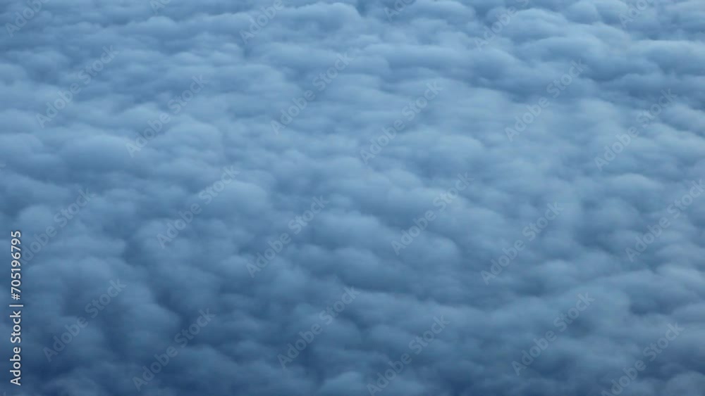 puffy clouds in late day blue light outside an airplane flying through the air (sky seen from plane window) moving sky, air travel puffy clouds in late day blue light outside an airplane flying through the air (sky seen from plane window) moving sky, air travel