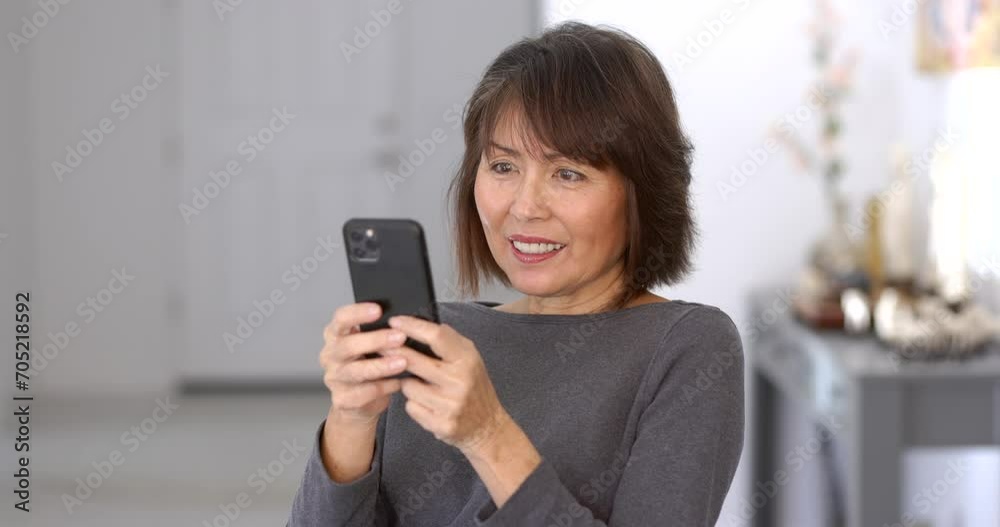 Smiling attractive woman enjoying texting reading mobile cell phone email messages relaxing sitting in home living room. Smiling attractive woman enjoying texting reading mobile cell phone email messages relaxing sitting in home living room.