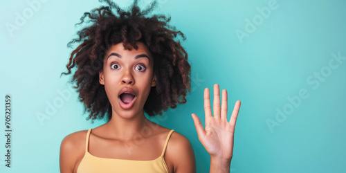 Excited Black Woman in Yellow Tank Top with Wide-Eyed Expression on Teal Background