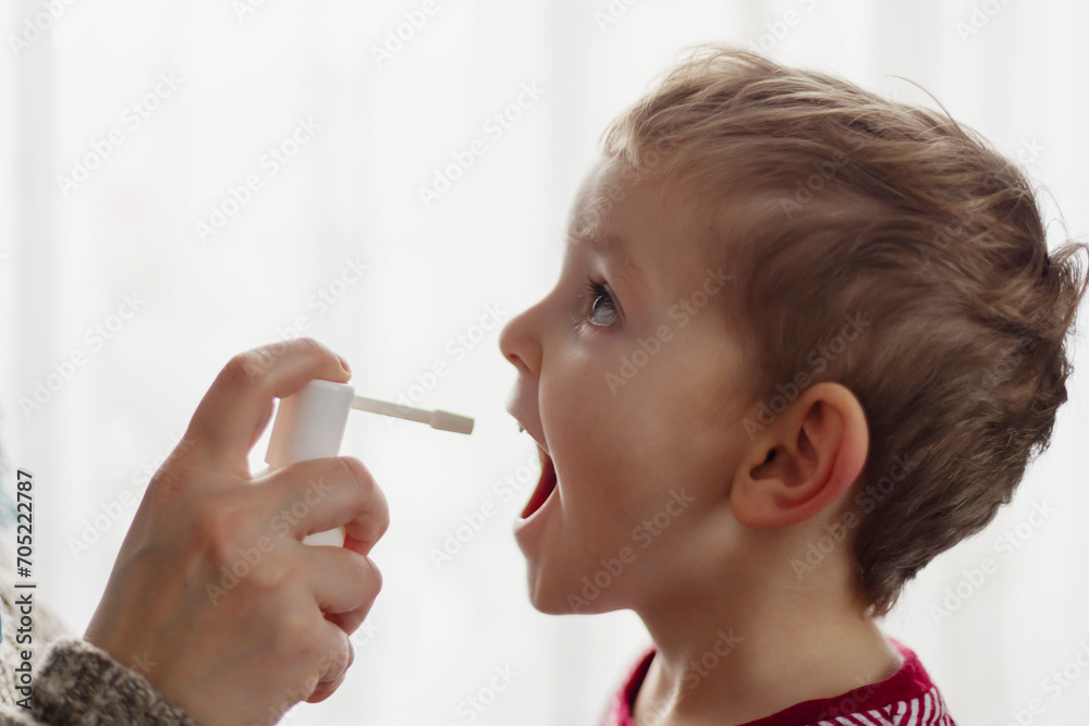 The child receives medication through a mouth spray for a sore throat The child receives medication through a mouth spray for a sore throat