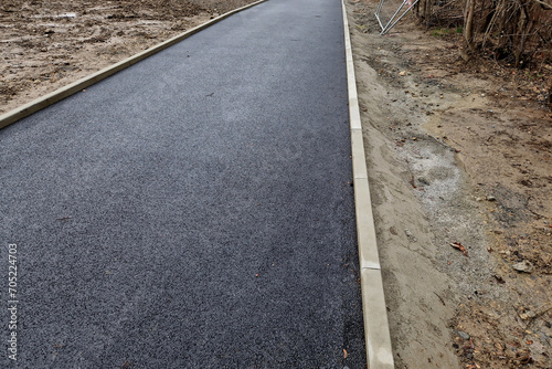 installation of concrete curb into concrete. in the space of the road, which so far has only a concrete base before laying the asphalt layer and rolling. mason, masonry, technology, slanted edge