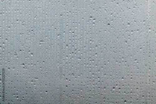A foggy sheet of transparent plastic with a mesh structure. Water drops are arranged in lines. Close-up. Background. Texture.