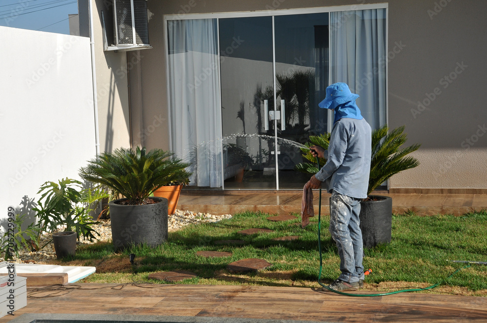 trabalhador molhando as plantas no jardim 