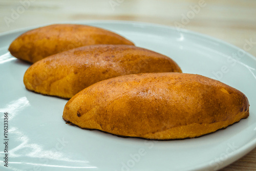 Three baked golden pastry pies with filling on a white plate.