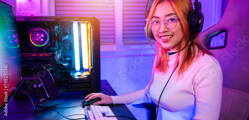 Smiling young woman wearing gaming headphones intend to do playing live stream games online at home looking to camera, Happy Gamer endeavor plays online video games tournament with computer neon light