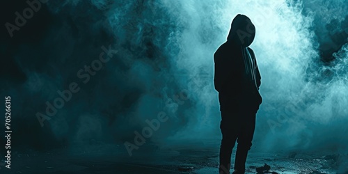 Silhouette of a man wearing a hoodie standing in a dark background