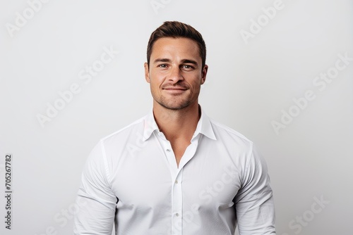 Handsome young man in white shirt standing against white background. © Igor