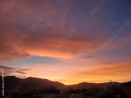 Warm sunset view on the horizon behind the mountains in the city © New