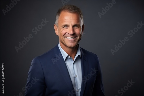 Portrait of a handsome mature businessman smiling at the camera over grey background.