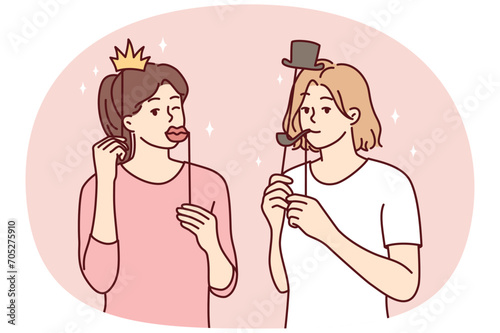 Girl friends with funny masks for photo shoot during house party or holiday carnival. Young casual women put cardboard lips and smoking pipe or crown with hat on their face. Flat vector illustration