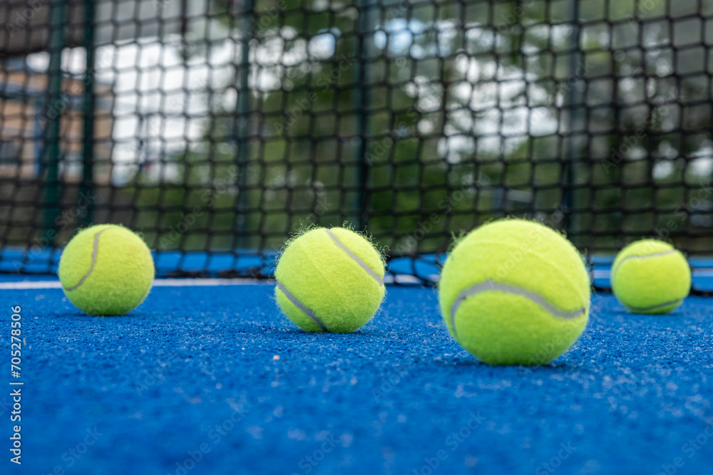 selective focus, four balls on a paddle tennis court with the net in the background