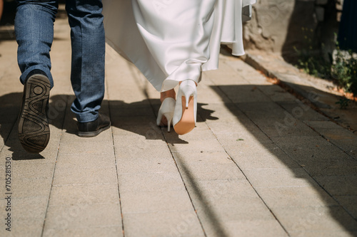 The image depicts a pair of peoples legs and shoes standing on a sidewalk. 5223