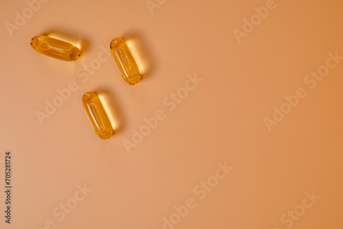 Omega 3 fish oil gel capsules on peach color background. Cod liver oil tablets, vitamins and supplements. View from above in random order. Copy Space.