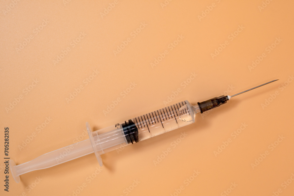 Full 5ml syringe with needle on peach background. Copy Space. Full 5ml syringe with needle on peach background. Copy Space.