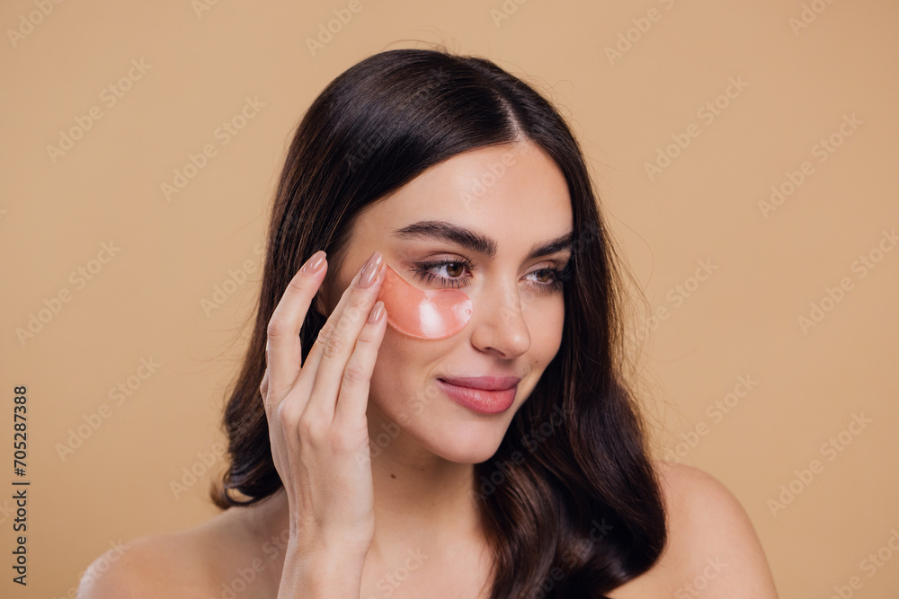 Beauty portrait of happy woman applying pink hydro gel pathches on her eyes Beauty portrait of happy woman applying pink hydro gel pathches on her eyes