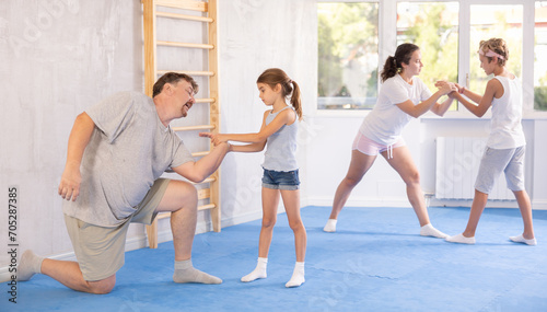 Parent and child train and perform basic punches and creases during self-defense lesson. Parent coach in teaches child effective protection during wrestling and dueling, martial arts.