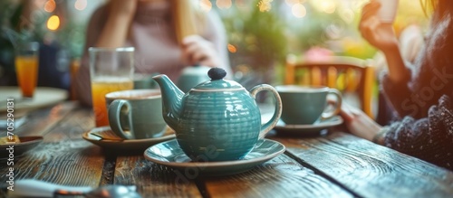 Unseen people enjoy hot drinks from stylish teapot and cups on a beautiful table. photo