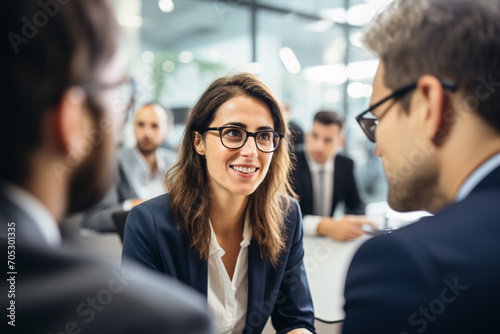 A woman smiles confidently during a business meeting in a modern office with her colleagues.