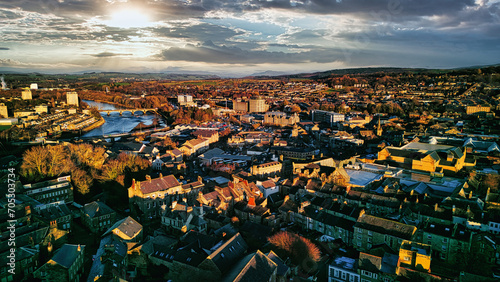 Aerial view of a city Lancaster at sunset with warm lighting, highlighting the urban landscape and river.